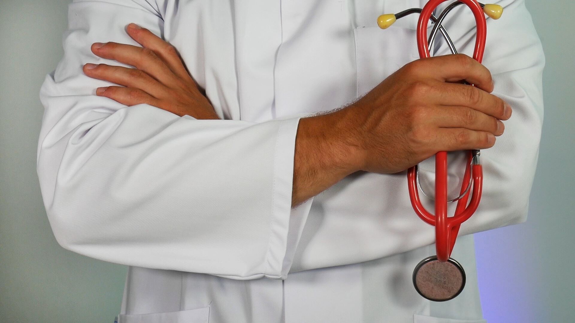 a man wearing a white clinician jacket holding a stethoscope