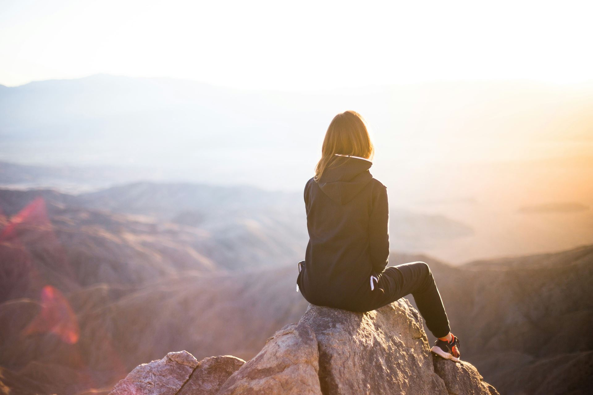 silhouette of a woman sat on a hill looking at the view