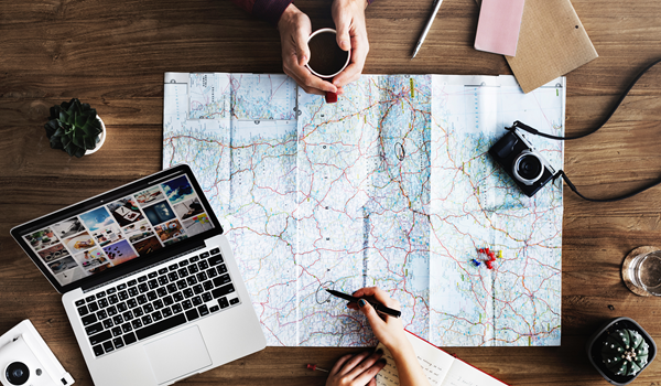 People sat at a table with a map, a camera and a computer